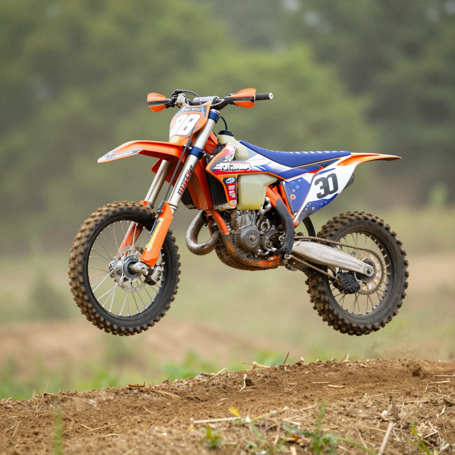 Dirt bike with custom graphics mid-air over a jump on a motocross track, kicking up dust